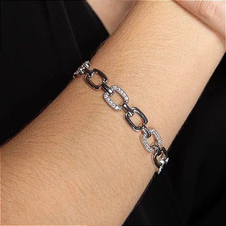 Pulseira de elos prateados com detalhes cravejados sobre fundo neutro