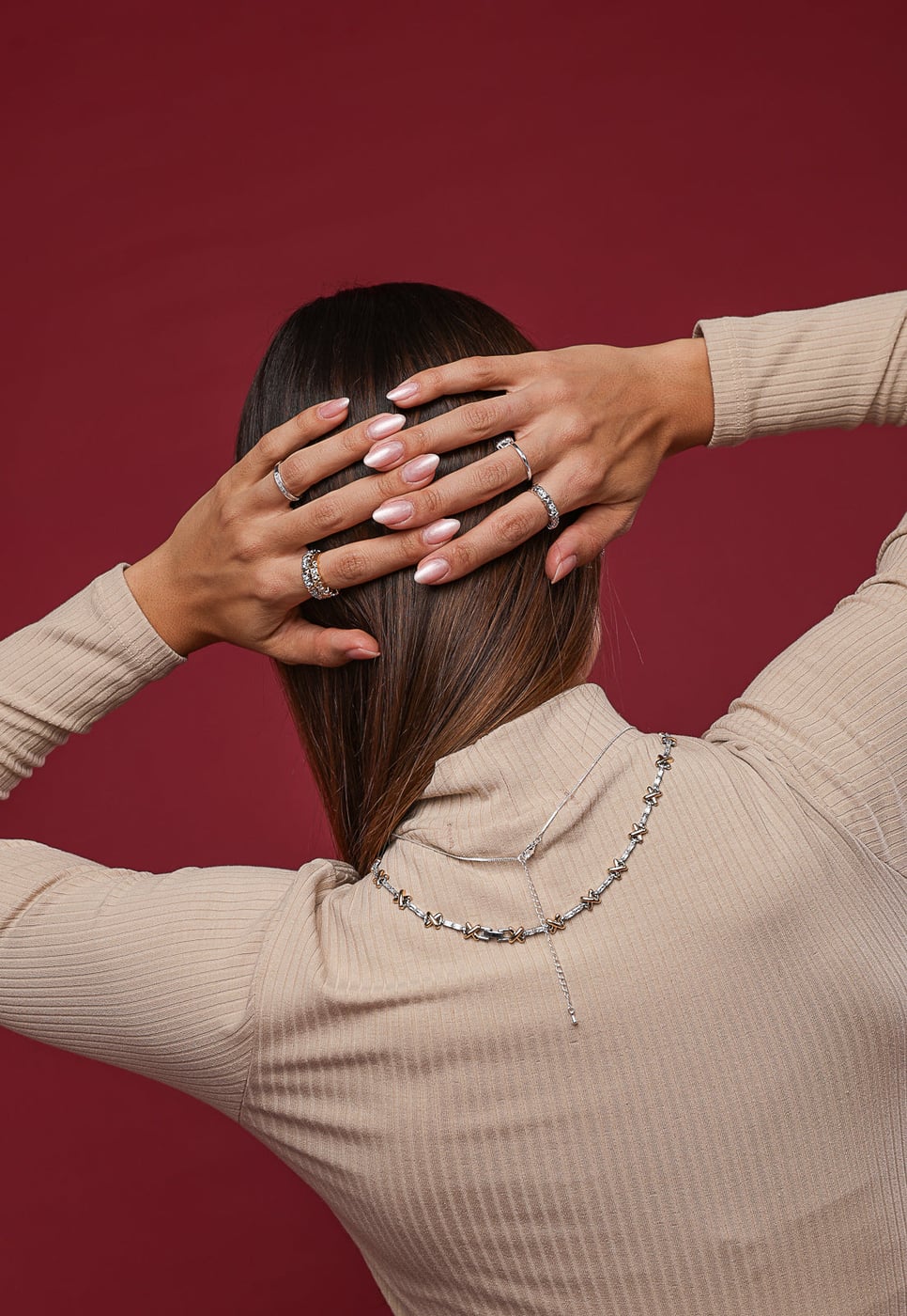 Mão feminina usando anel prateado com pedras no dedo anelar